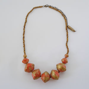 Orange hand made ethical design paper bead necklace made out of recycled paper in Uganda by principles of fair trade, ethical and sustainable fashion, empowering women of post war area, by Finnish / Scandinavian brand, Agulu Paper Beads. Eettinen oranssi käsintehty design kaulakoru, joka on tehty kierrätyspaperista reilun kaupan periaattein työllistämällä Ugandalaisia nasia.