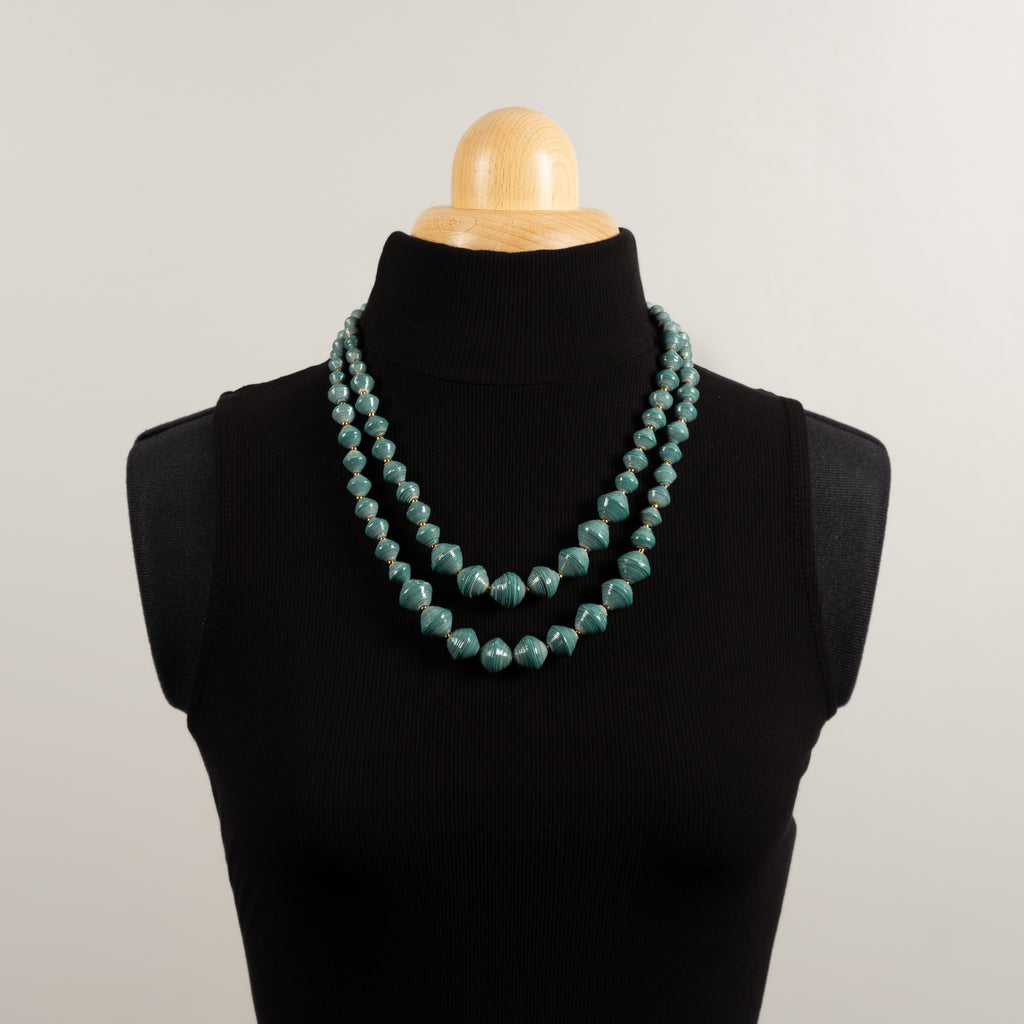 Hand made design paper bead necklace made out of petrol blue recycled paper in Uganda by principles of fair trade, ethical and sustainable fashion, by Finnish brand, Agulu Paper Beads. Eettinen käsintehty design kaulakoru, joka on tehty petroolinvärisestä kierrätyspaperista reilun kaupan periaattein työllistämällä Ugandalaisia naisia.