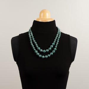 Hand made design paper bead necklace made out of petrol blue recycled paper in Uganda by principles of fair trade, ethical and sustainable fashion, by Finnish brand, Agulu Paper Beads. Eettinen käsintehty design kaulakoru, joka on tehty petroolinvärisestä kierrätyspaperista reilun kaupan periaattein työllistämällä Ugandalaisia naisia.